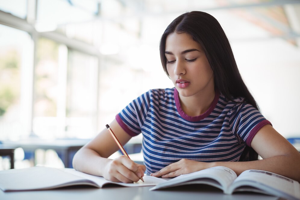 attentive-schoolgirl-doing-homework-classroom_107420-75398