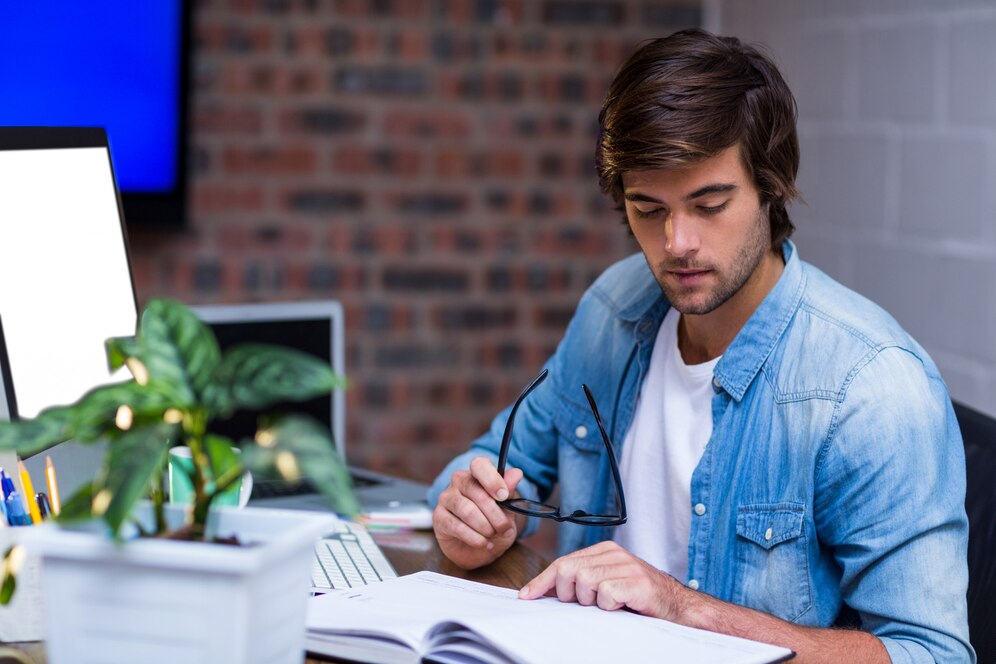 businessman-reading-book-desk_107420-56490